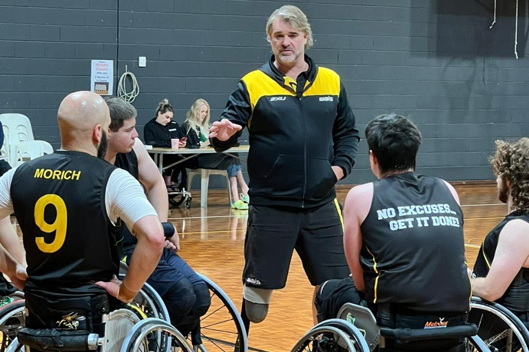 Coach Brad Ness chatting with wheelchair basketball athletes