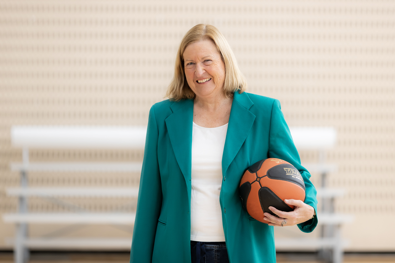 A woman wearing business/professional attire holding a basketball.