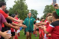 A rugby 7s player high fives players and children while running onto the field
