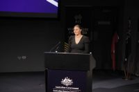 A woman stands behind a lectern on stage