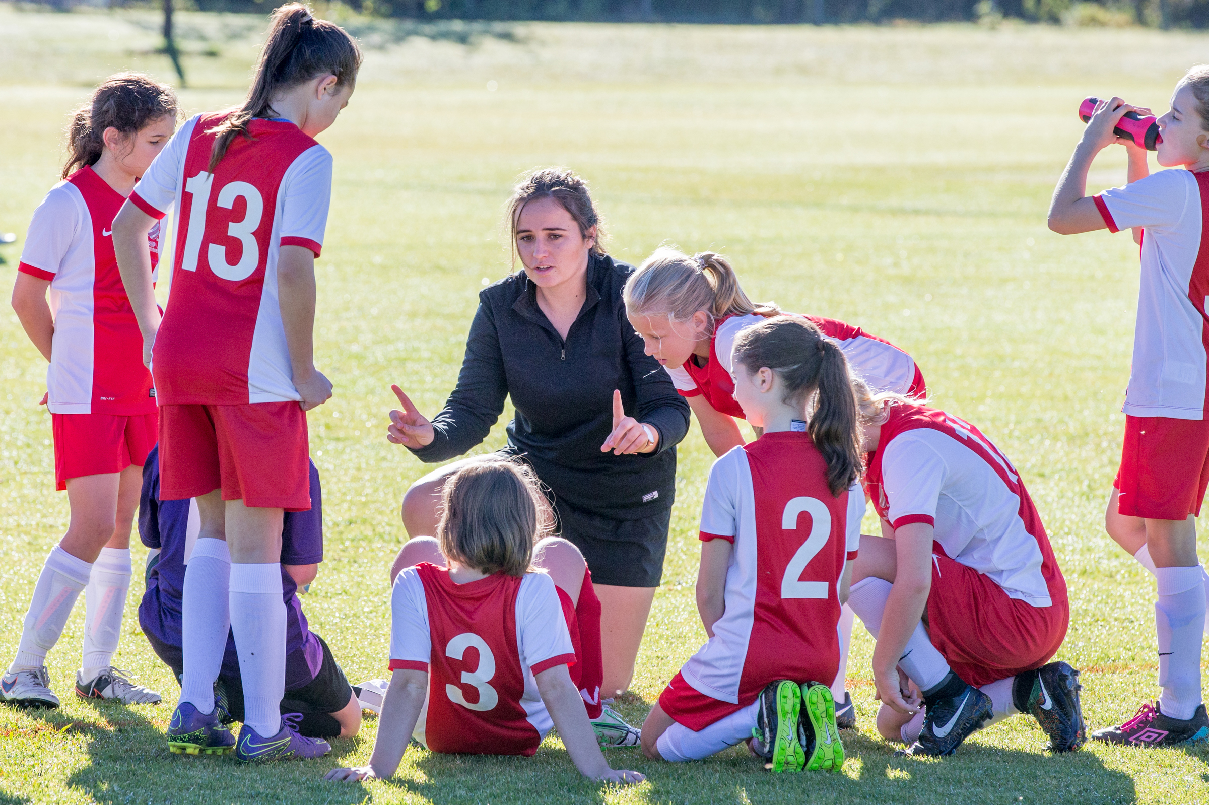 Woman coaches girls soccer or football in the park 