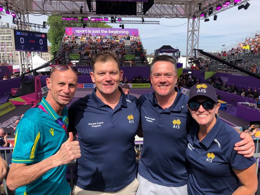 AIS coaches smile as they stand in front of the Commonwealth Games venue