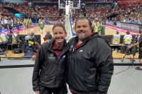 Amanda Jones and another volunteer stand courtside while the Australian Opals basketball team train in the background.