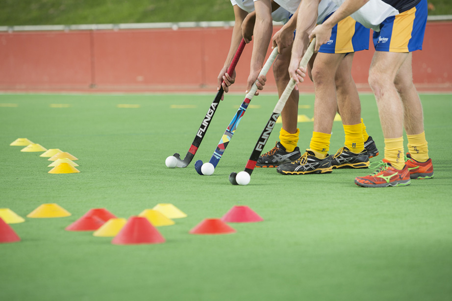 Image of hockey players legs and sticks preparing for a training drill.