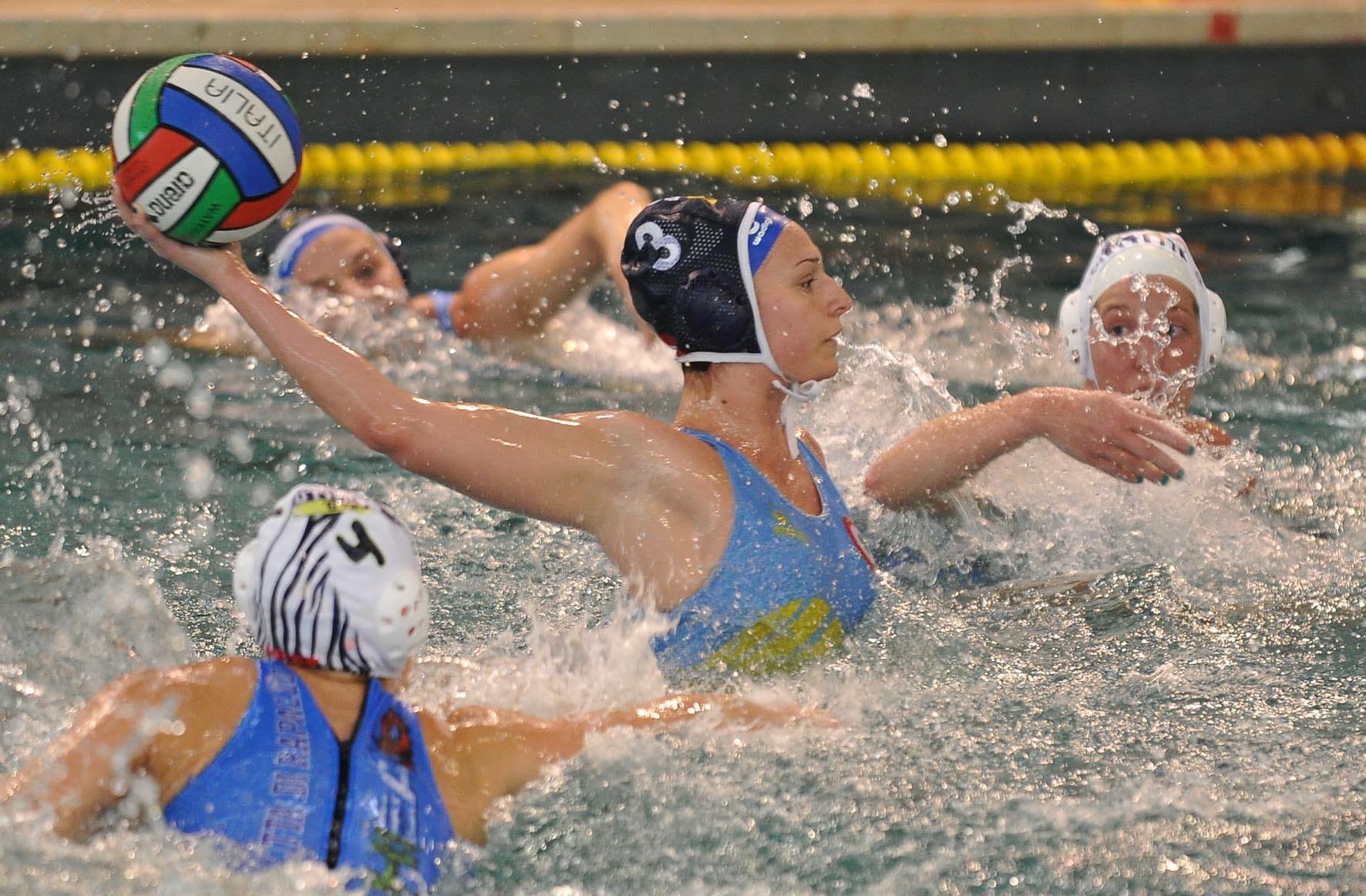 Image shows a water polo player leaping out of the water attempting to shoot the ball.