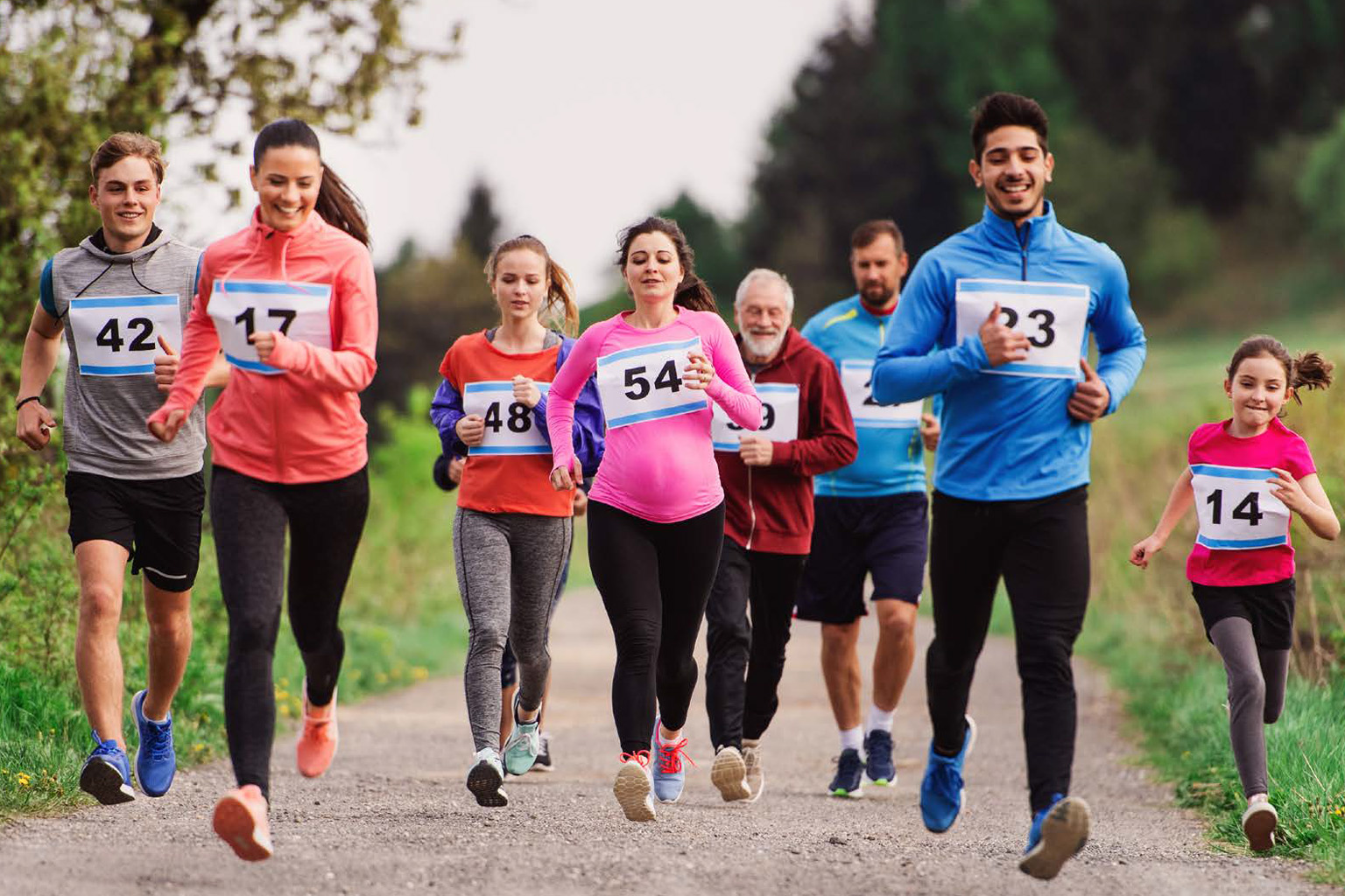 A group of men and women run together wearing numbered bibs