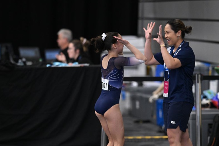 A gymnast and her coach high five