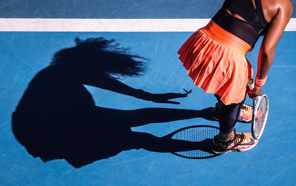 A silhouette of Naomi Osaka shows a butterfly resting on her finger.