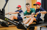 Olympian Alex Purnell helps Melba Copland Secondary School students train on a rowing machine.