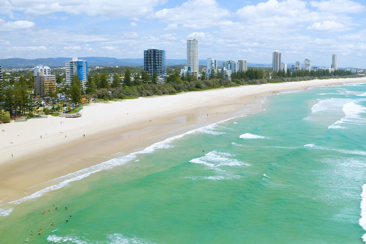 Aerial view of Gold coast from above the ocean, looking back over high-rise buildings.