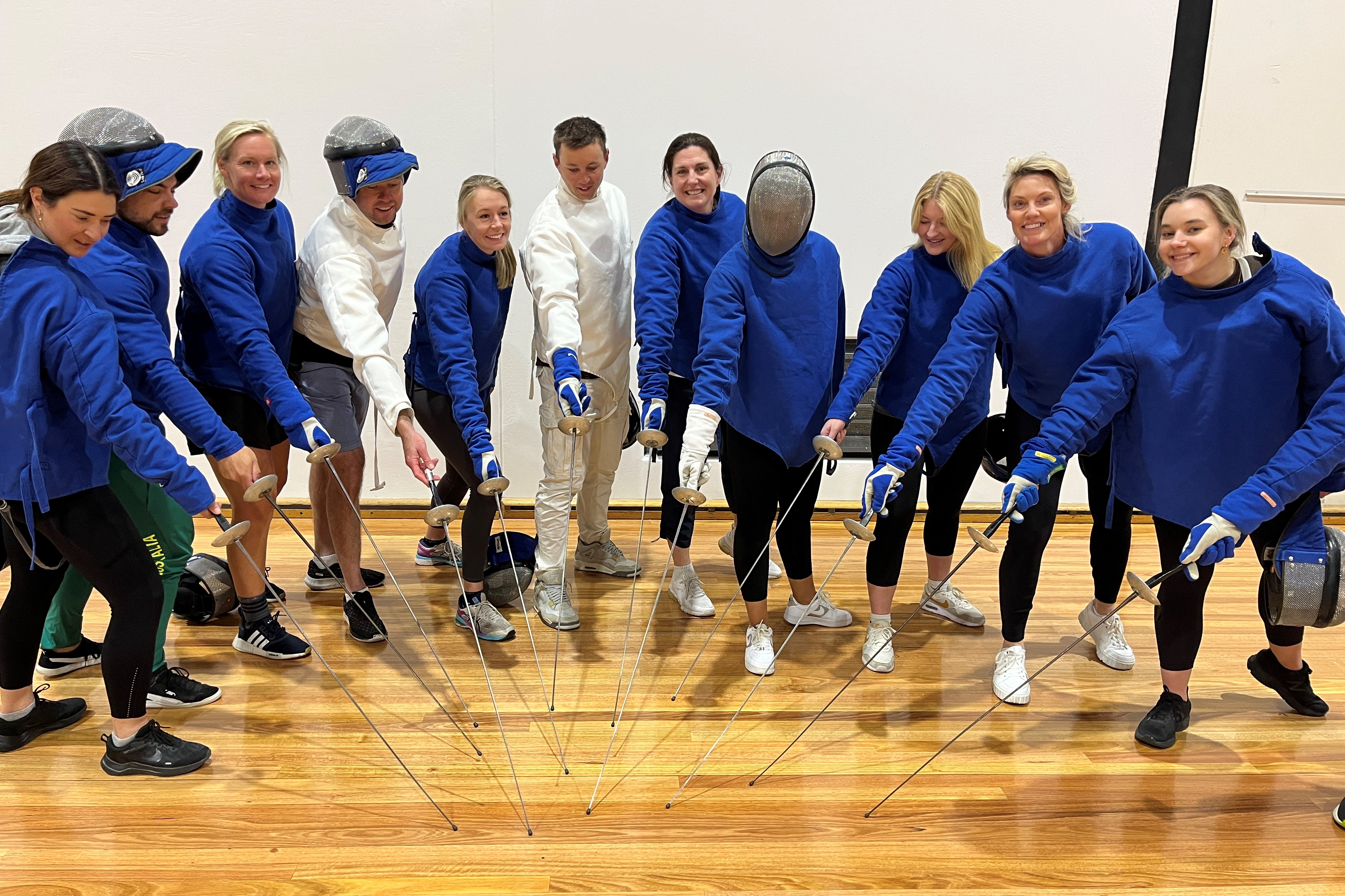 Coaches stand in group dressed in fencing uniform.