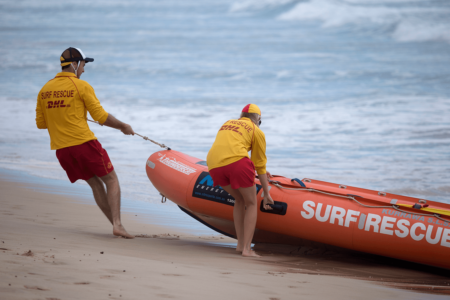 Two life guards pulling a rescue boat from the water