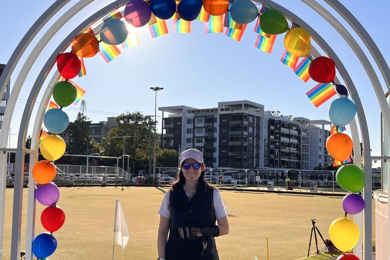 Para Jackaroo Serena Bonnell standing under a rainbow arch at the first all-inclusive Rainbow Versatility Pairs bowls tournament on the Gold Coast which welcomed people of all ages, backgrounds and abilities to compete.