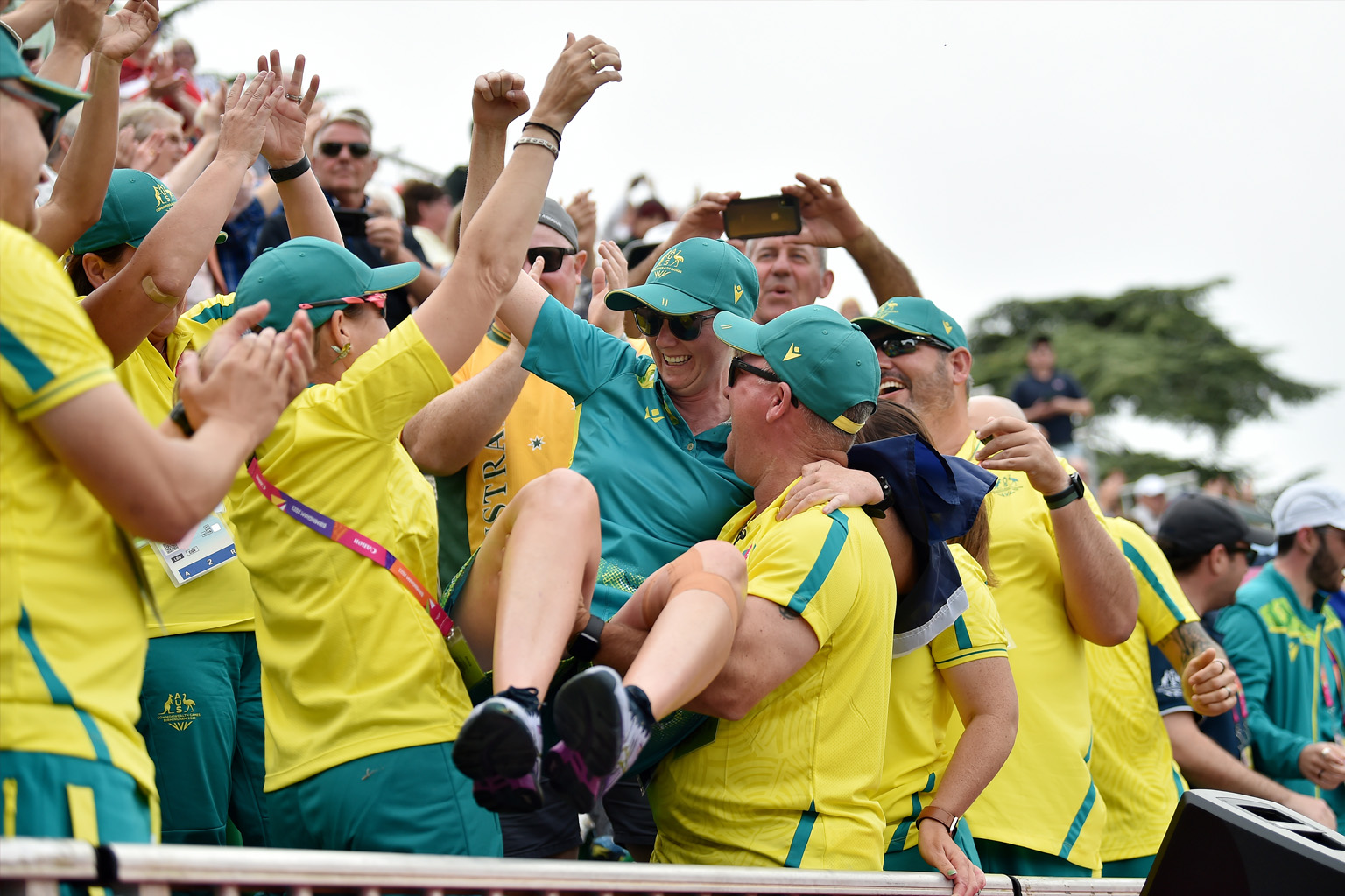 Members of Team Australia wearing green and gold uniforms hold up Ellen Ryan in celebration.