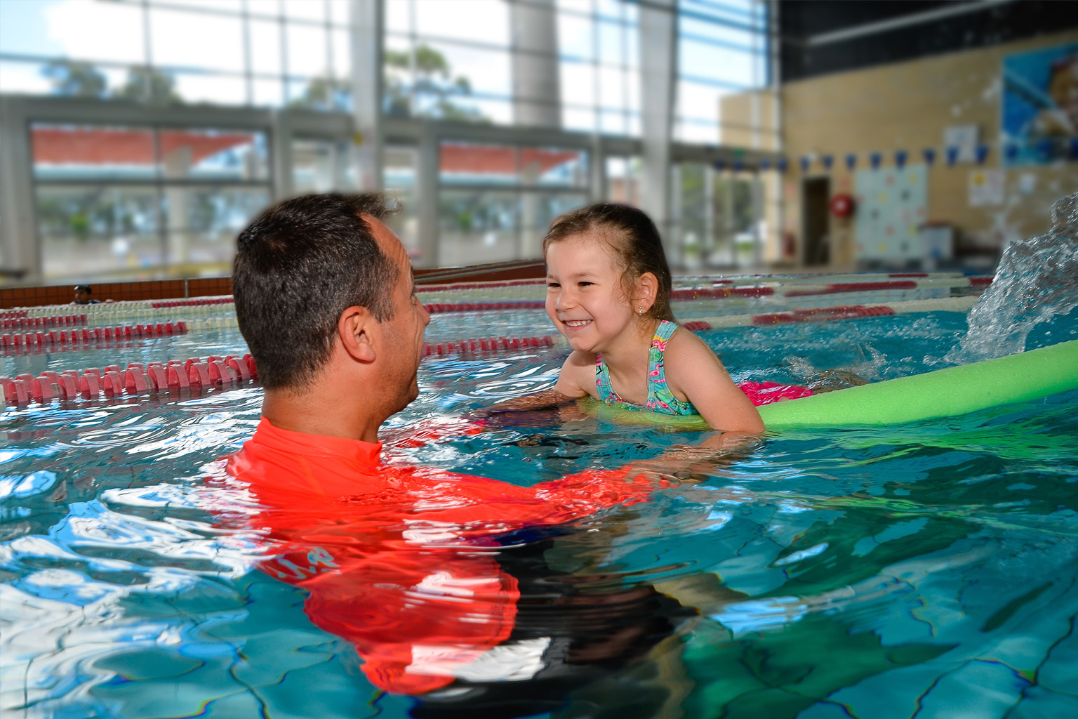 A swimming teacher helps a young child through the water.