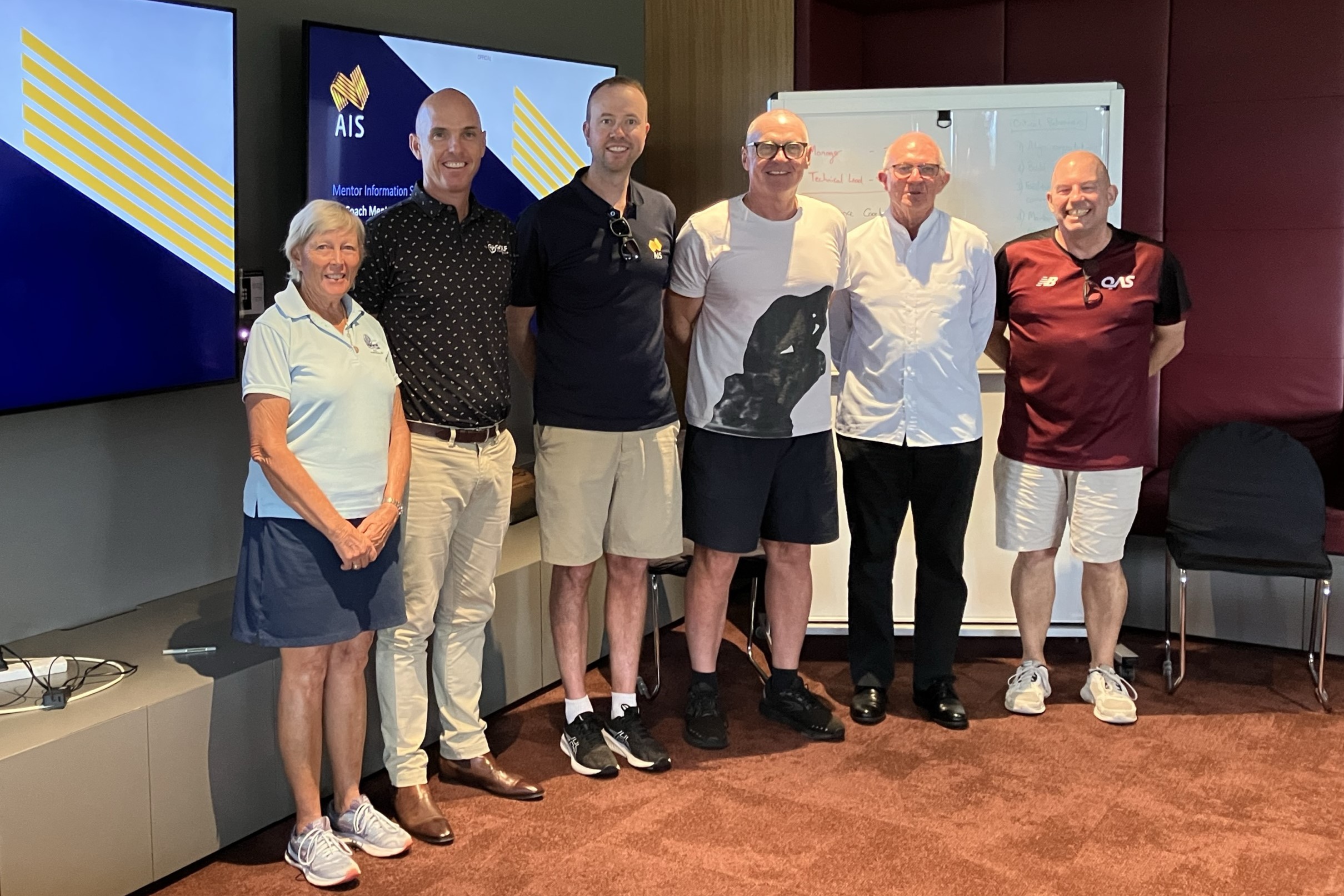 Coaches stand in front of presentation screen.