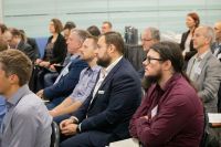 People seated, listening to a speaker