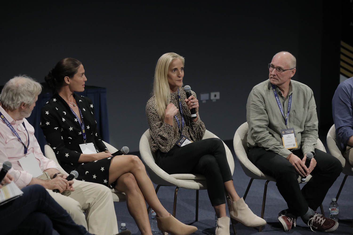 Four people sitting on stage, Nicole Hannan speaks into a microphone