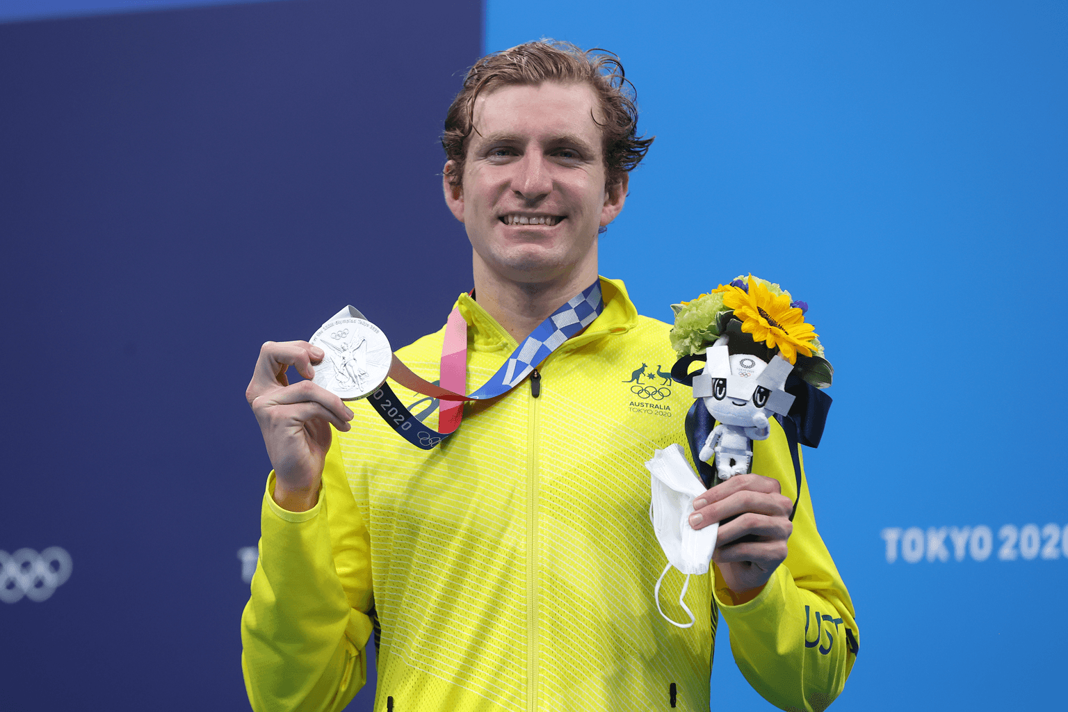 Australian Swimmer Jack McLoughlin holds up a silver medal and a toy mascot from the Tokyo 2020 Olympic Games.