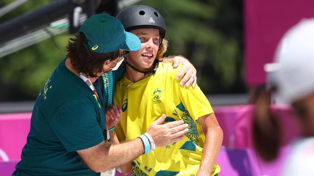A coach celebrates with a skateboarder after winning a medal. 