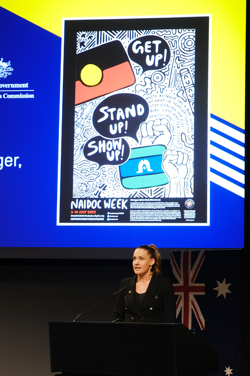 Kate Corkery stands in front of a NAIDOC poster