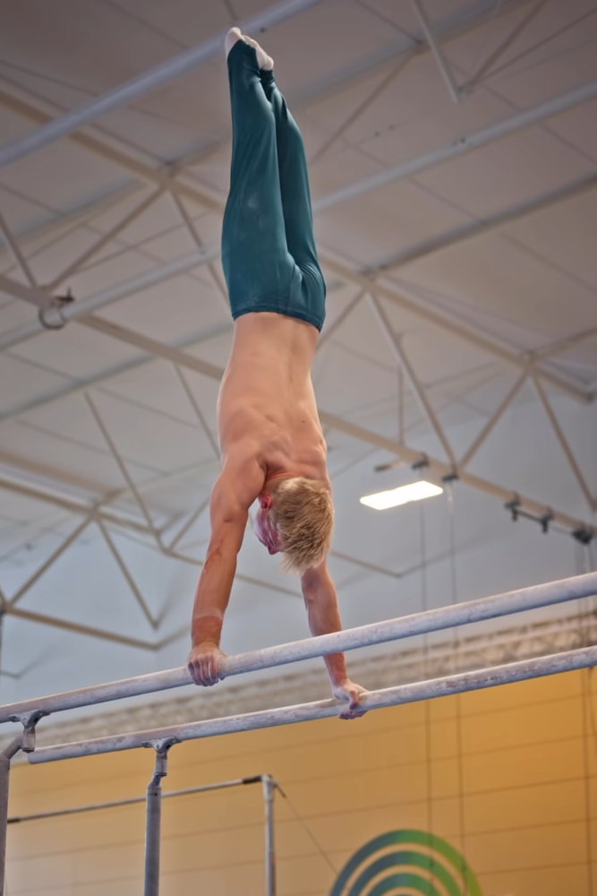 Gymnast upside down on bars.