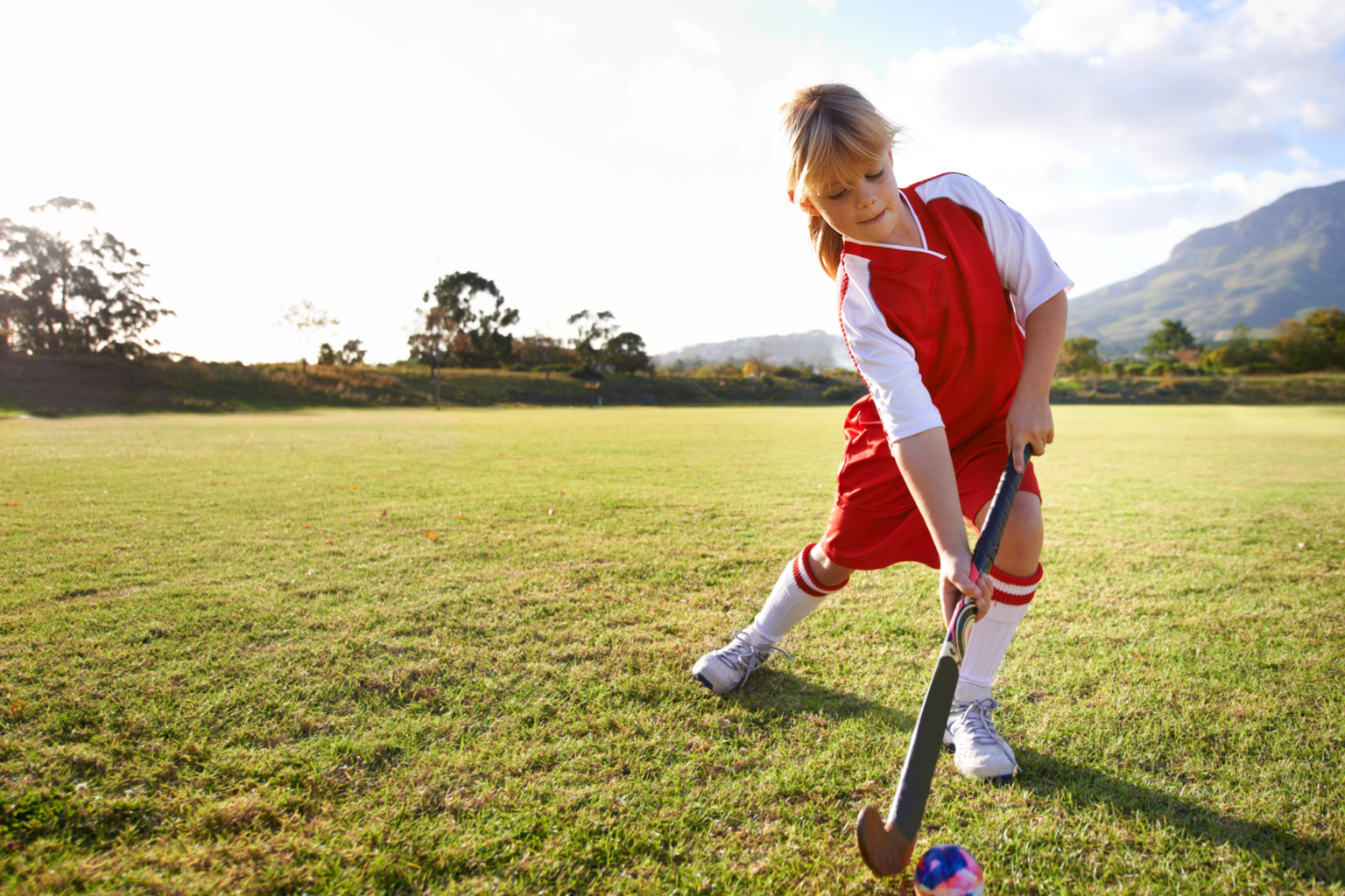 Child playing hockey in a field.