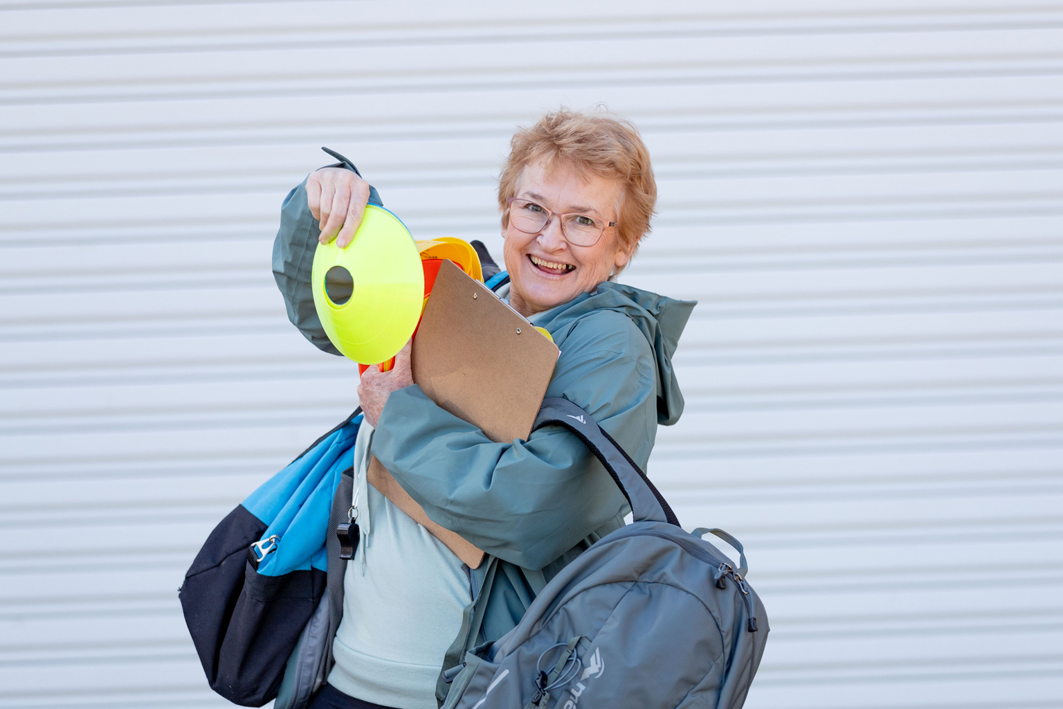 A woman smiles while juggling sporting bags and equipment