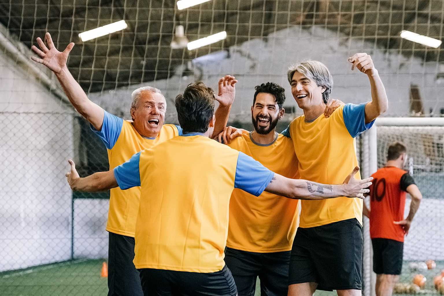 A group of men celebrate on an indoor sport field