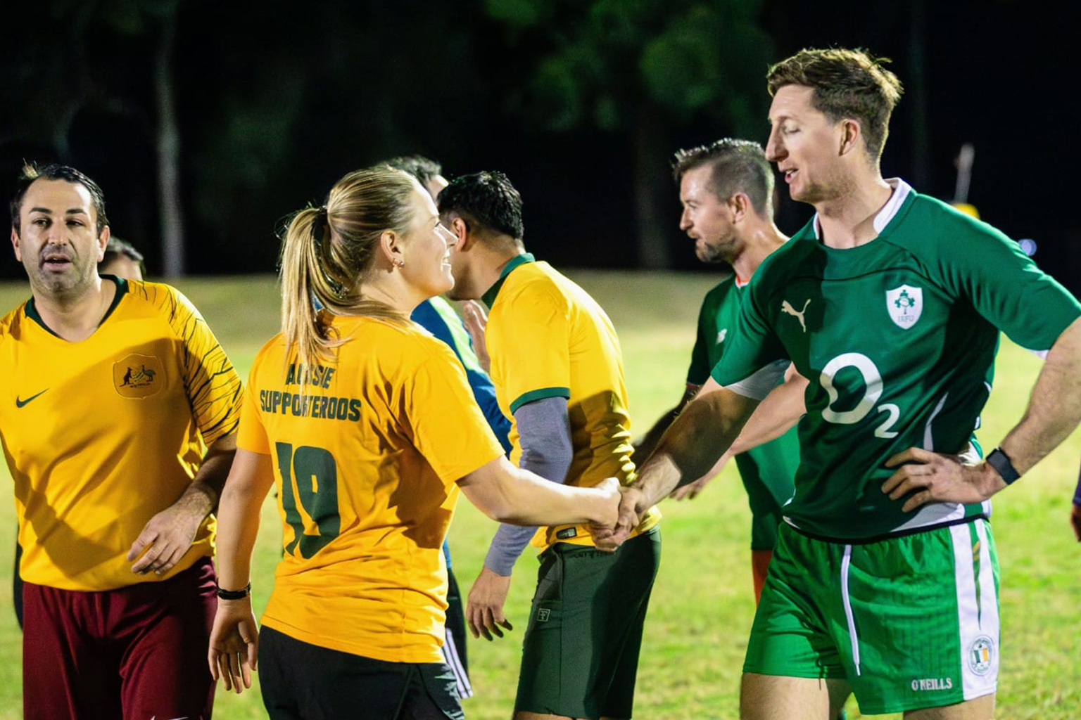 Players wearing yellow Aussie Supporteroos tops shake hands with players from Ireland.