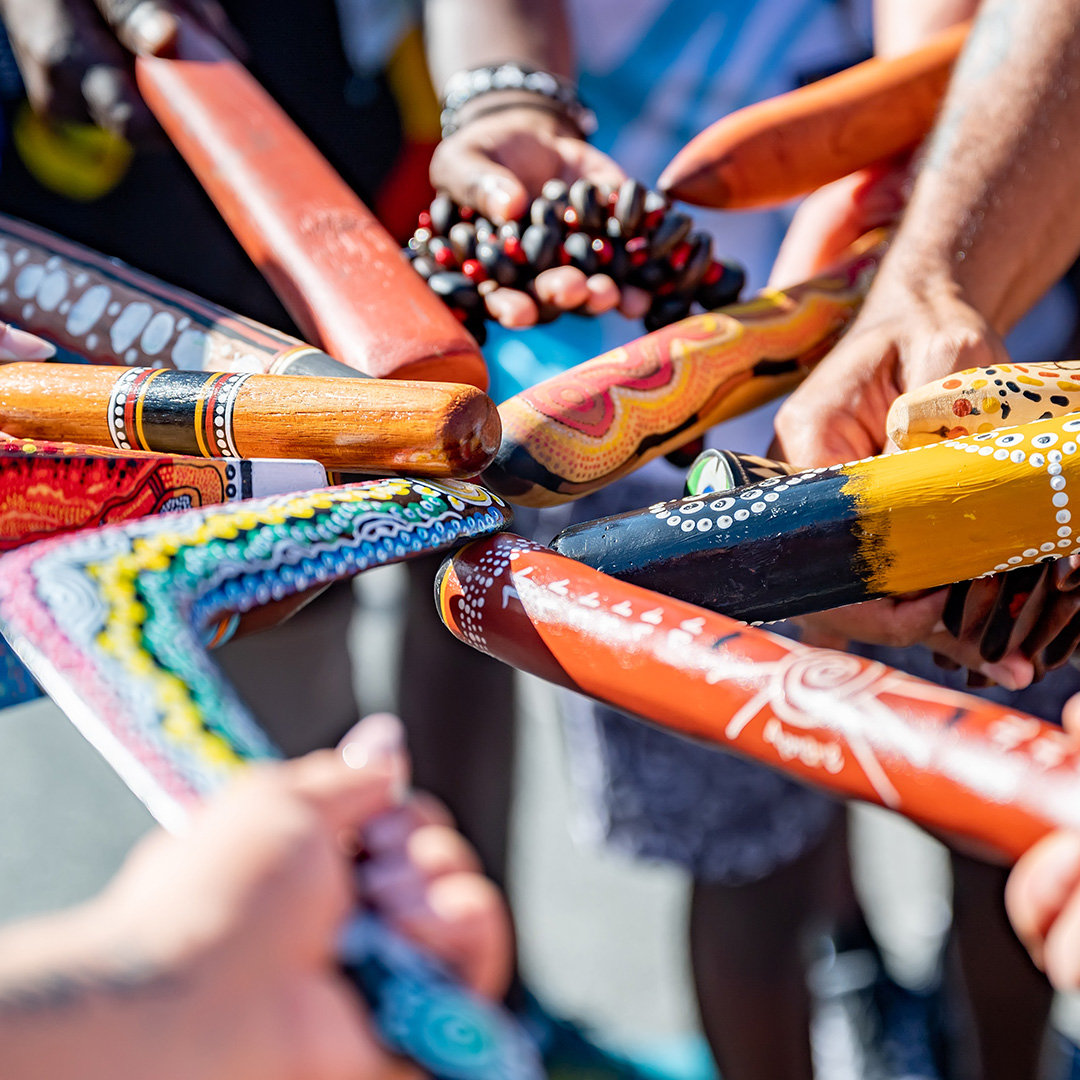 Colourful boomerangs and sticks decorated with Indigenous artwork held together in a circle 