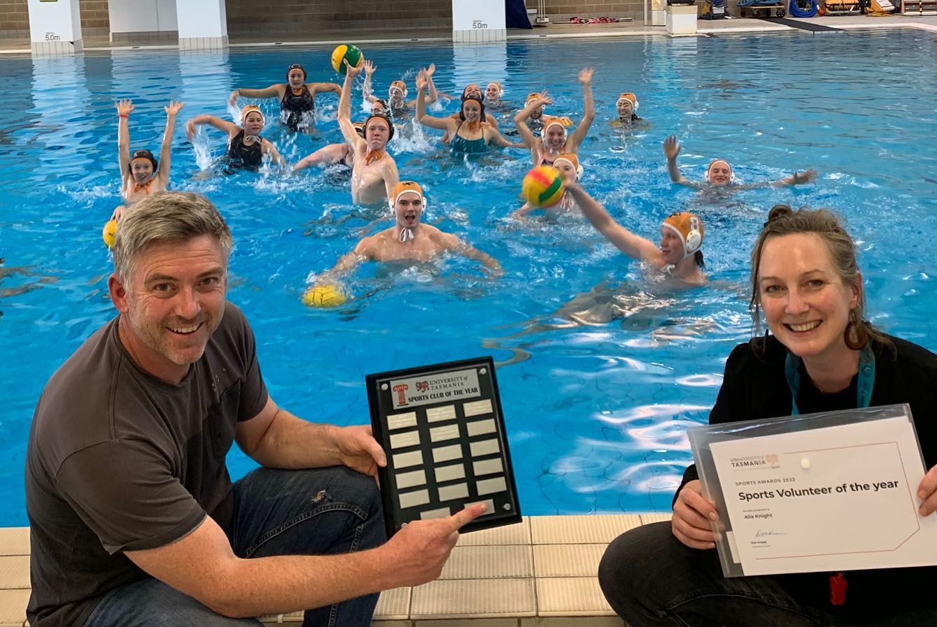 Alia Knight holds a Sports Volunteer of the Year certificate poolside with members of the Honey Badgers Water Polo Club in the water