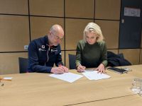 two people sign document at table