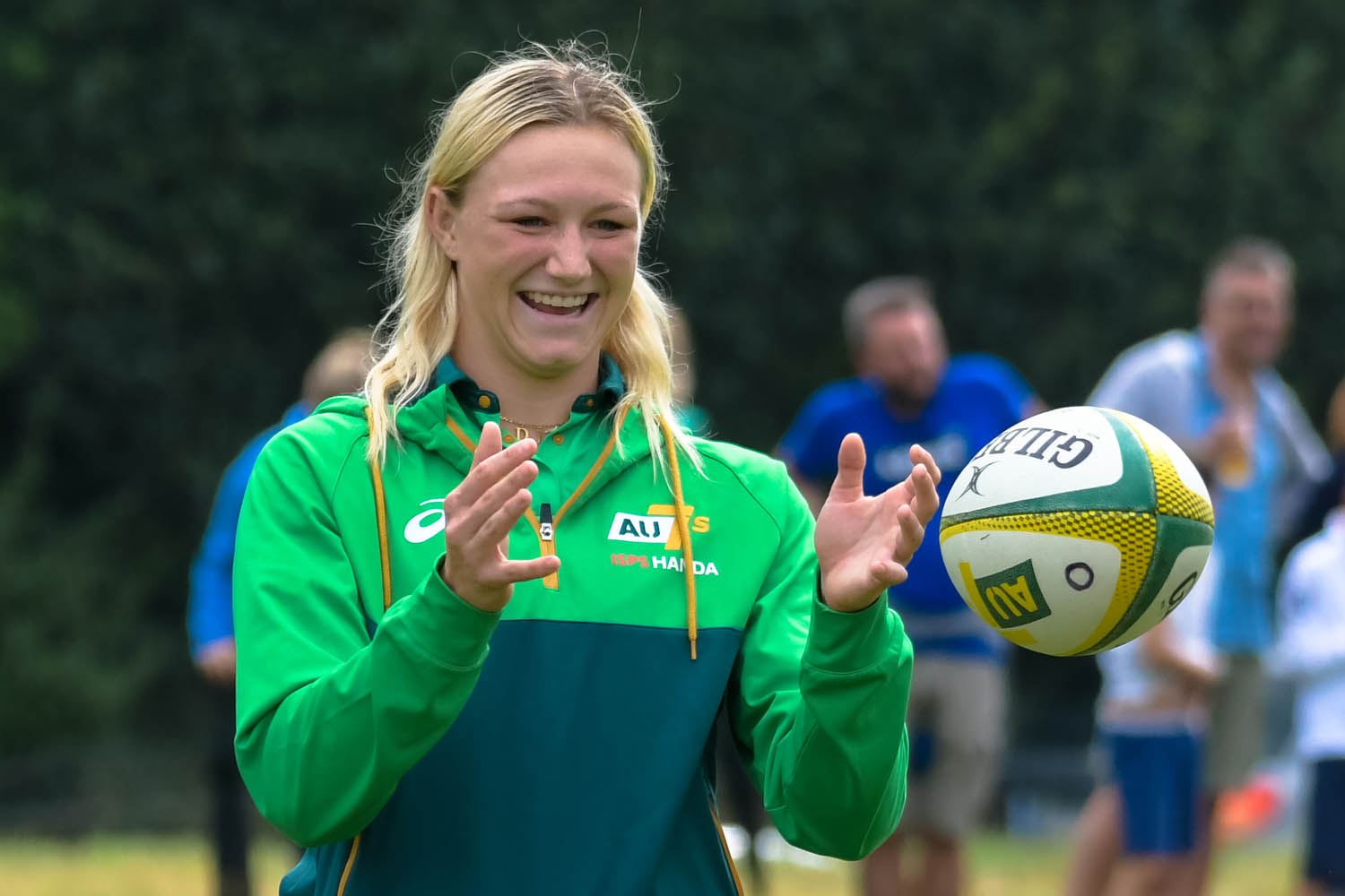 A woman smiles while catching a Rugby ball